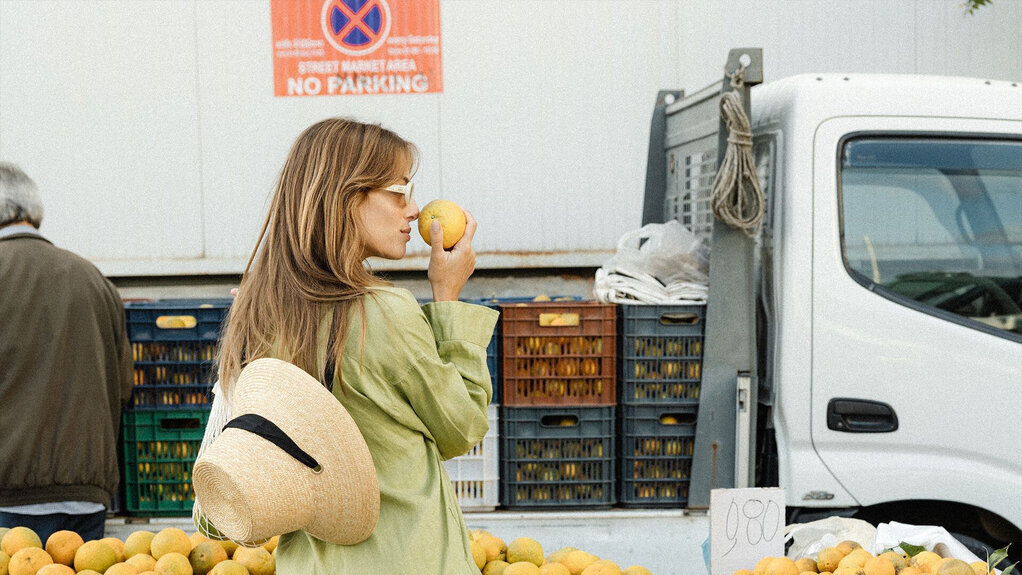 Female traveler sampling the fruits at a local market in Rethymno in September, and for some, the best time to visit Crete for less crowds and more local immersion.